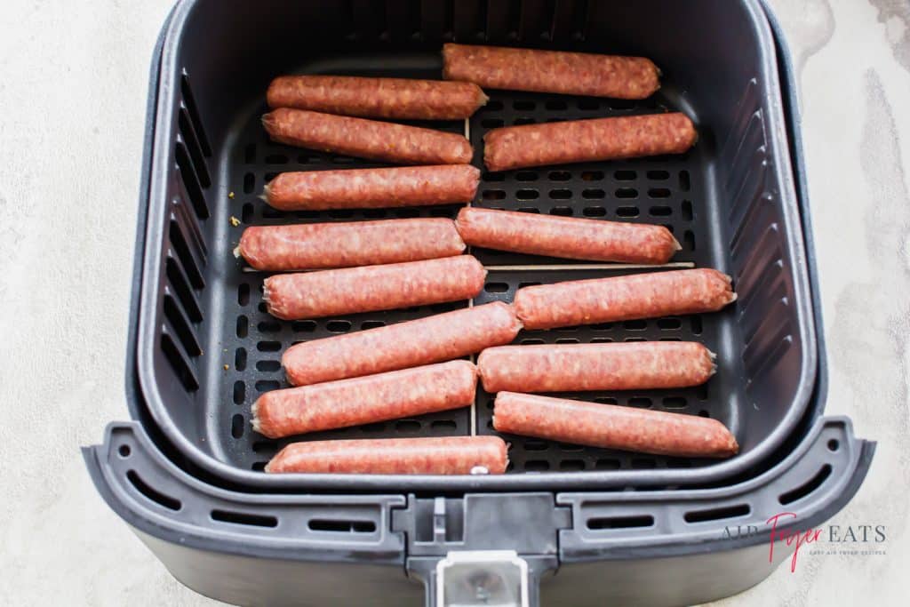 a dozen raw fresh sausage links in a square air fryer basket