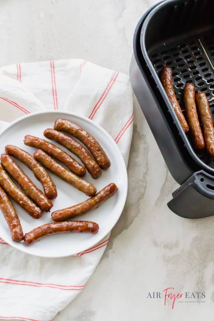 a white plate of sausage links next to an air fryer basket of sausage links. 