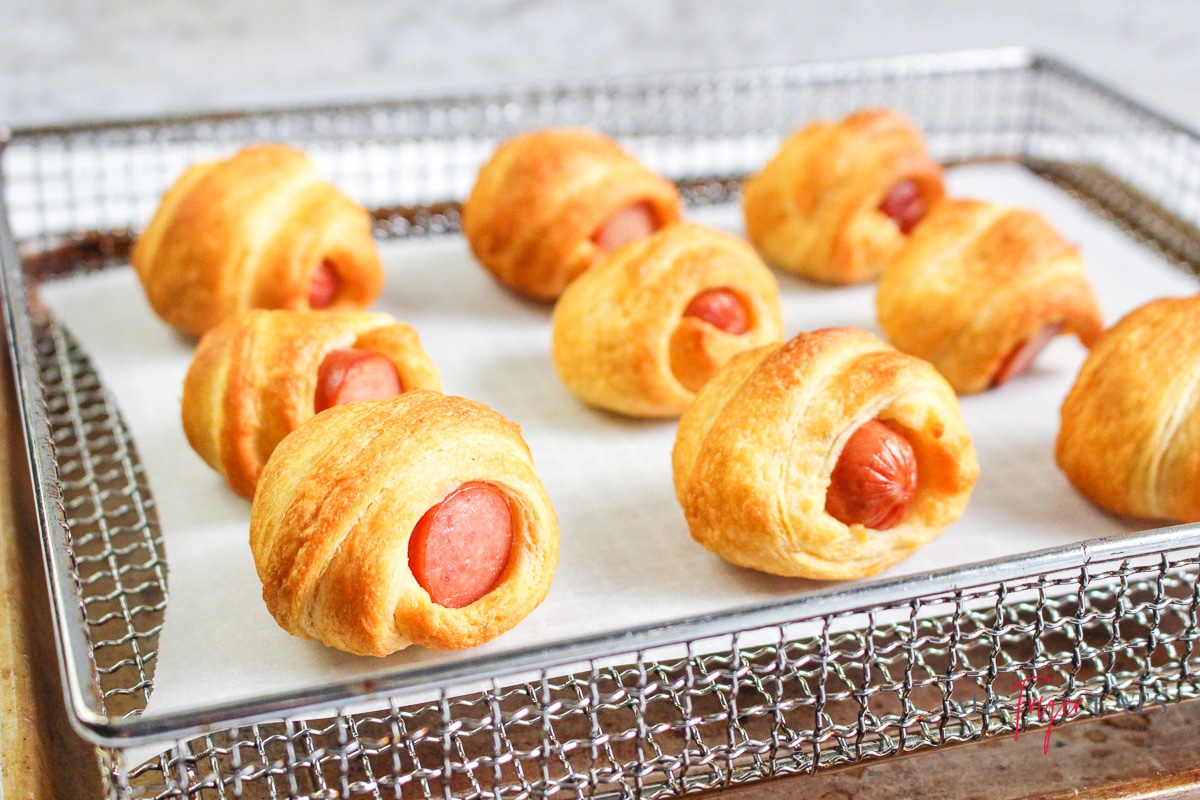 mini pigs in a blanket on an air fryer tray lined with parchment paper
