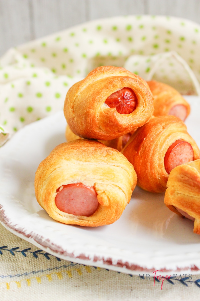 pigs in a blanket, piled on a white plate. 