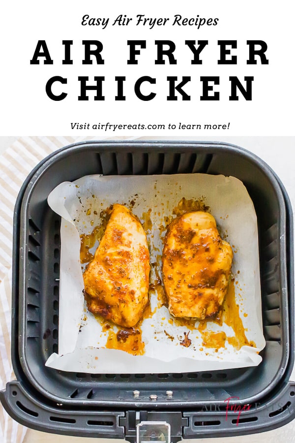 Two cooked chicken breasts in a square air fryer basket that has been lined with parchment paper. 