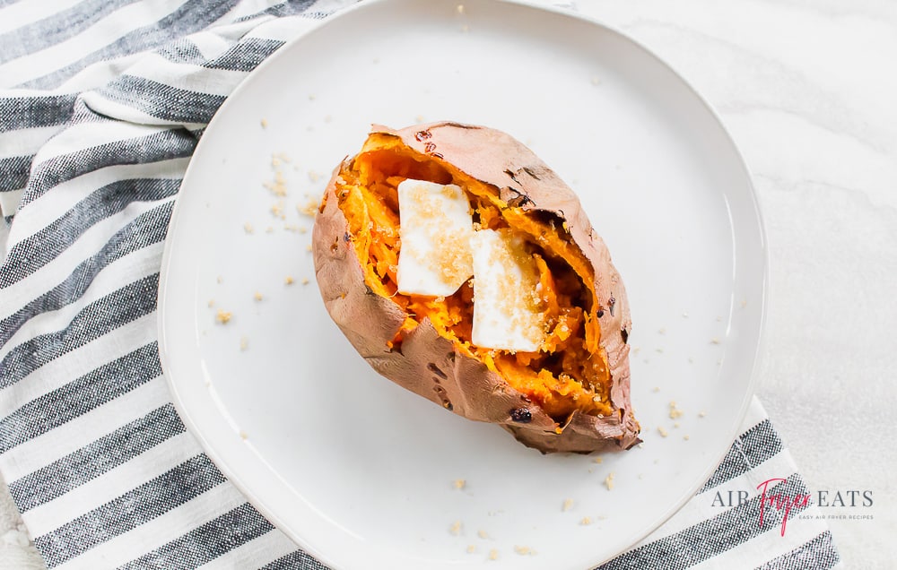 a sweet potato sliced open with butter and sugar on top