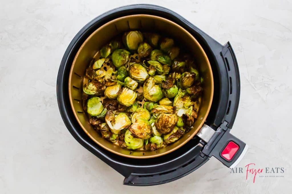 a round air fryer basket filled with air fried browned brussel sprouts