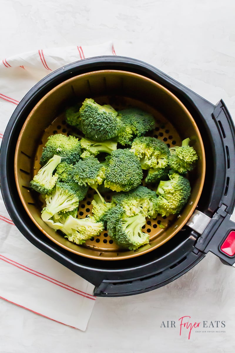 a pile of broccoli in the basket of an air fryer