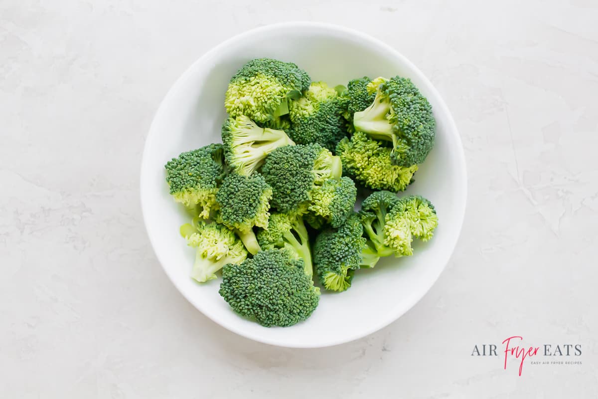 green raw broccoli in a white bowl on a white background