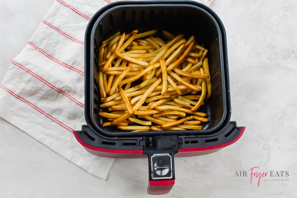 cooked fries in the square shaped basket of a red air fryer