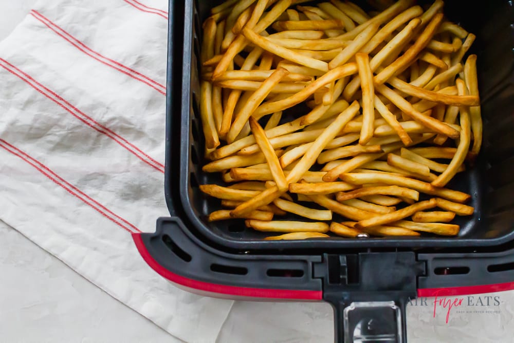 fresh cooked golden brown french fries in an air fryer basket 