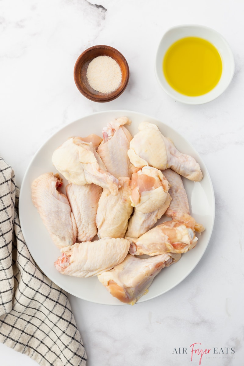 a plate of raw chicken wings, and seasonings are the ingredients needed to make chicken wings in the air fryer