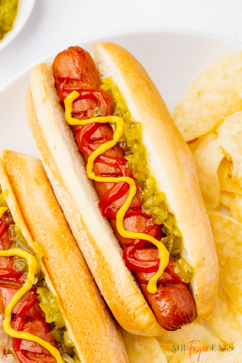 closeup view of a hotdog in a bun, topped with ketchup, mustard, and relish.