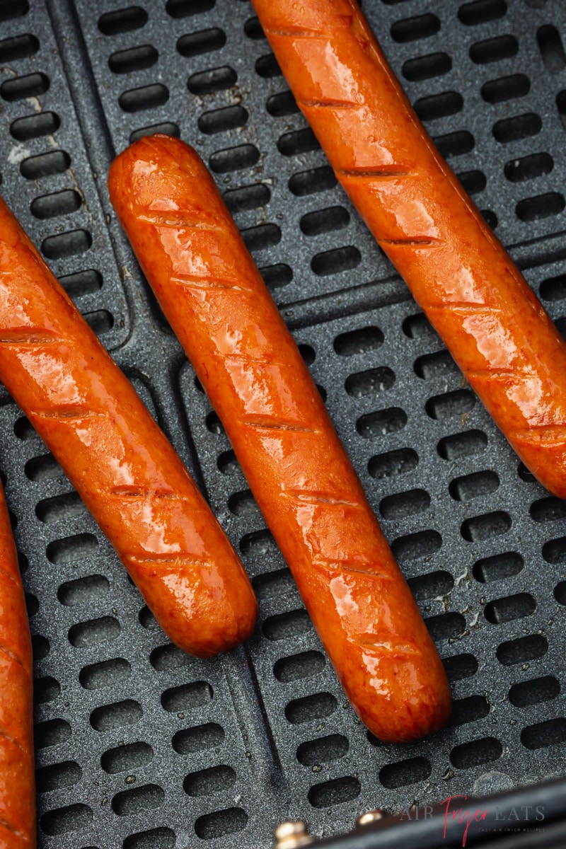 Cooked hot dogs in an air fryer basket, close up