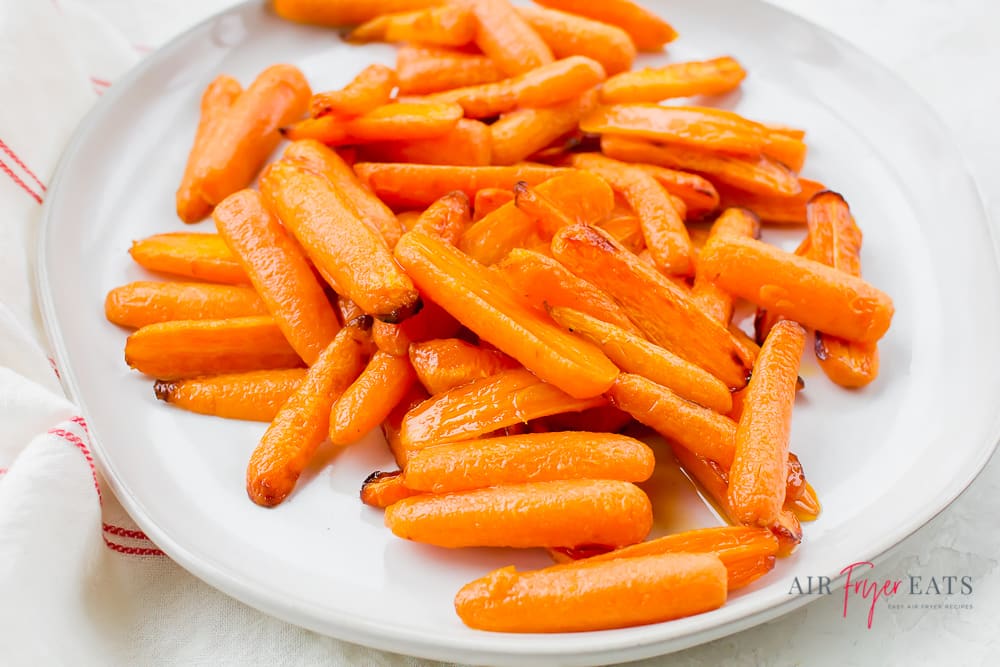 shiny orange halved air fryer baby carrots on white plate