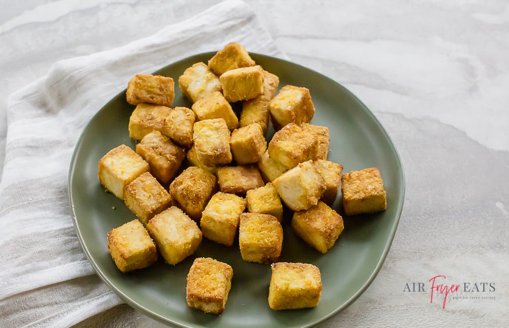 a pile of brown air fried tofu bites on a gray plate