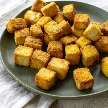 cooked light brown colored cubes of tofu on a gray plate