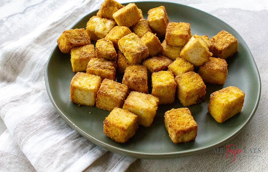 cooked light brown colored cubes of tofu on a gray plate