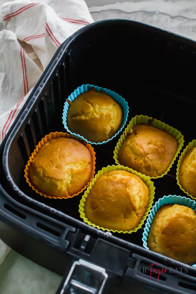 black air fryer basket containing 6 silcone cupcake molds holding cooked cupcakes