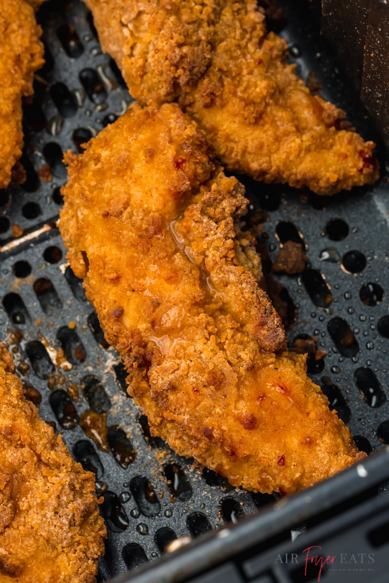 closeup view of a crispy chicken tender in an air fryer basket