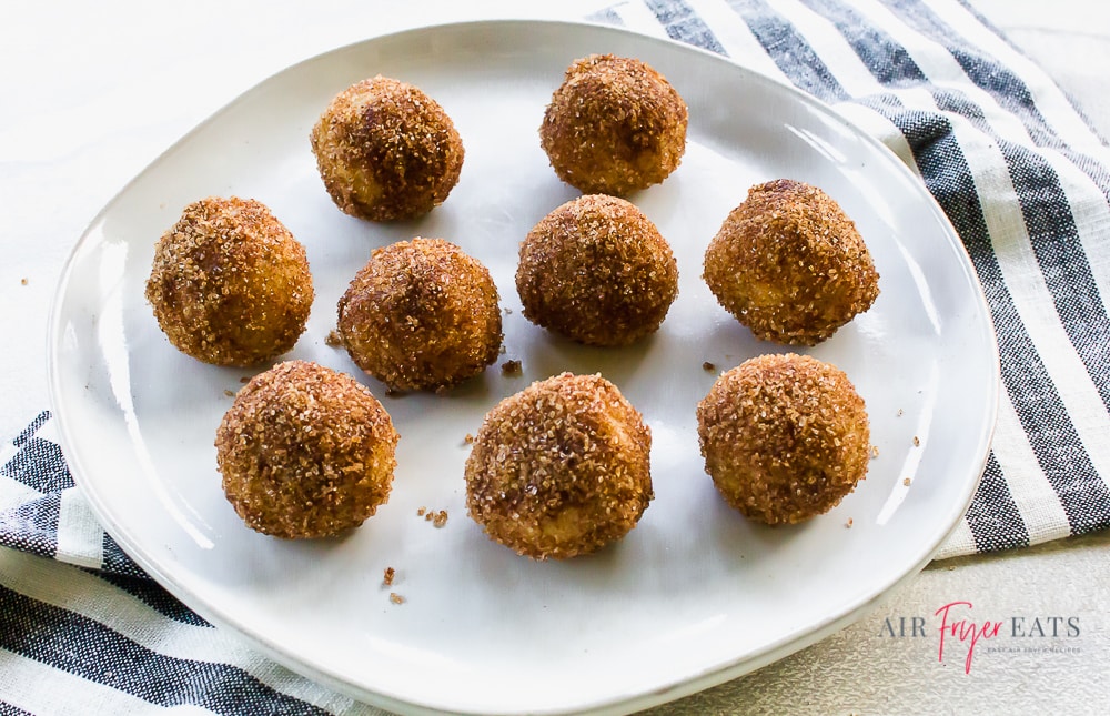 donut holes on a white plate with a black striped towel