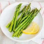 Asparagus and lemon wedges on a white plate