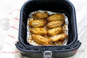 8 brown chicken wing pieces in a foil lined air fryer basket