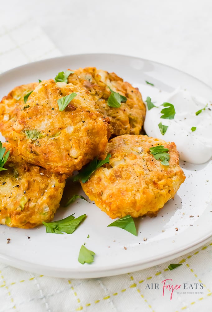 potato pancakes garnished with parsley on a white plate with sour cream