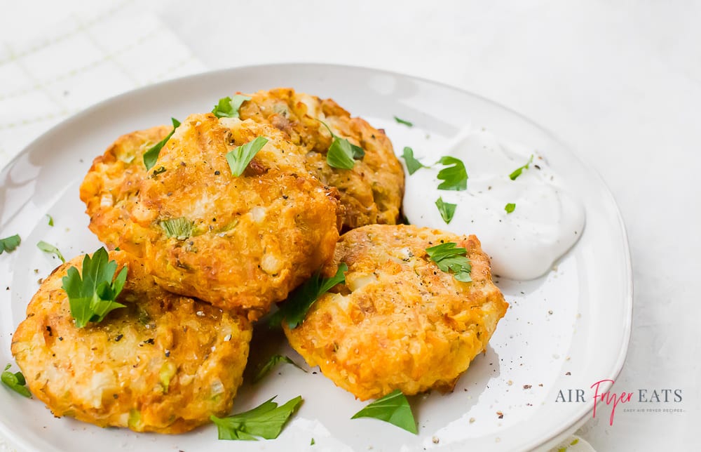 potato pancakes garnished with parsley on a white plate with sour cream