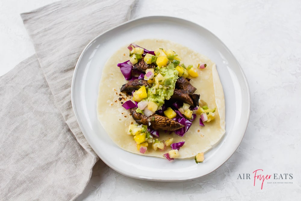 red cabbage, sliced portobello mushrooms, pineapple salsa, and guacamole on a tortilla