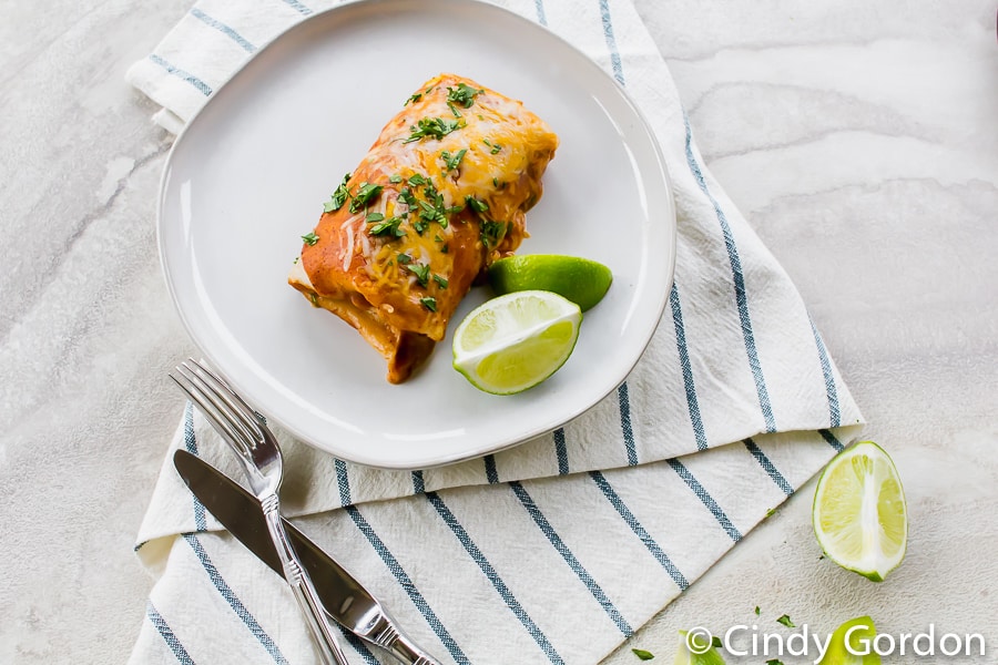 vegetarian enchiladas on a white plate with lime wedges on the side