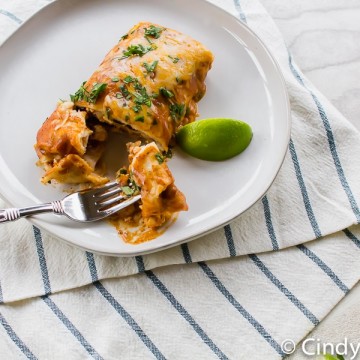 vegetarian enchiladas with a lime wedge on a white plate with a fork
