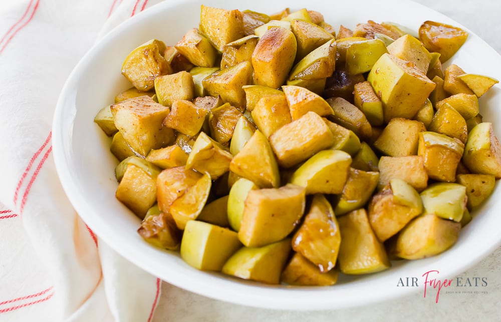 cooked sweet apples on a white plate with a red striped kitchen towel