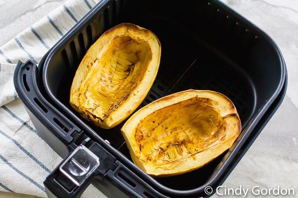 cooked spaghetti squash halves in an air fryer basket