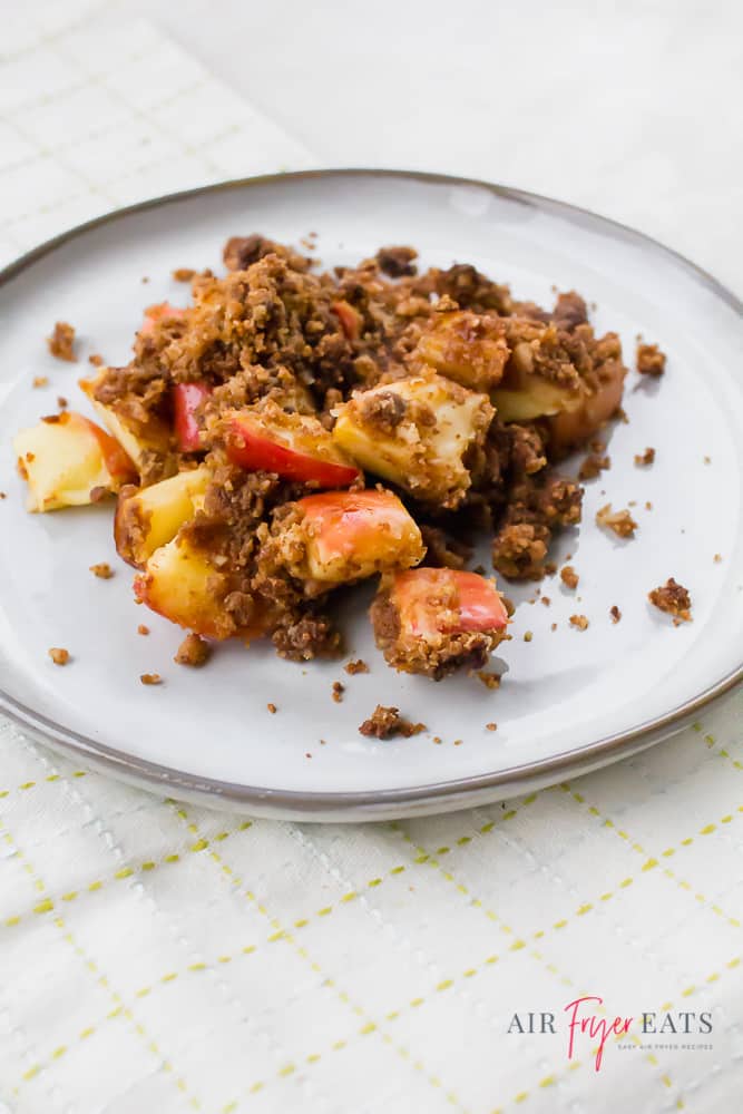 Air fryer apple crisp on a white plate on a white background.