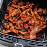 black air fryer basket full of cooked bacon