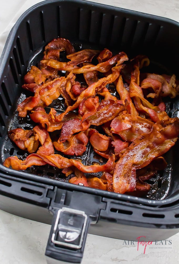 black air fryer basket full of cooked bacon