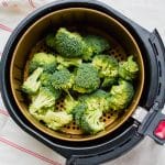 raw green broccoli in a round air fryer basket