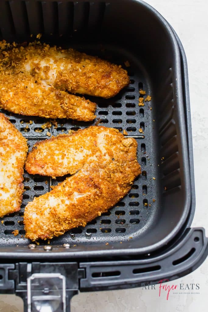 air fryer fish in a black air fryer basket. fish is cooked