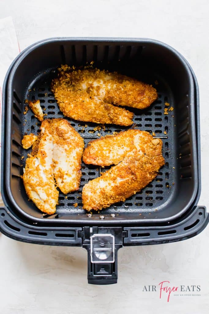 cooked air fryer fish in a black air fryer basket