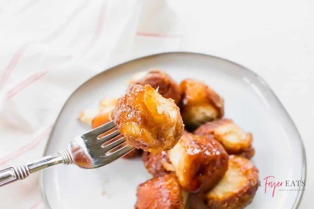 A bite of monkey bread on a silver fork over a white plate