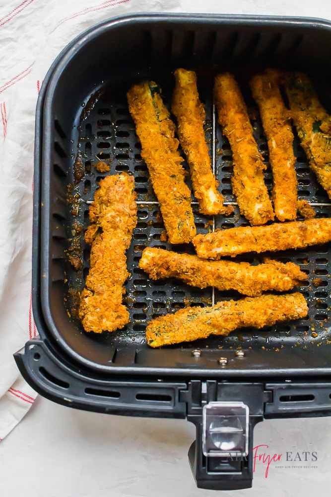 Cooked zucchini fries in an air fryer basket