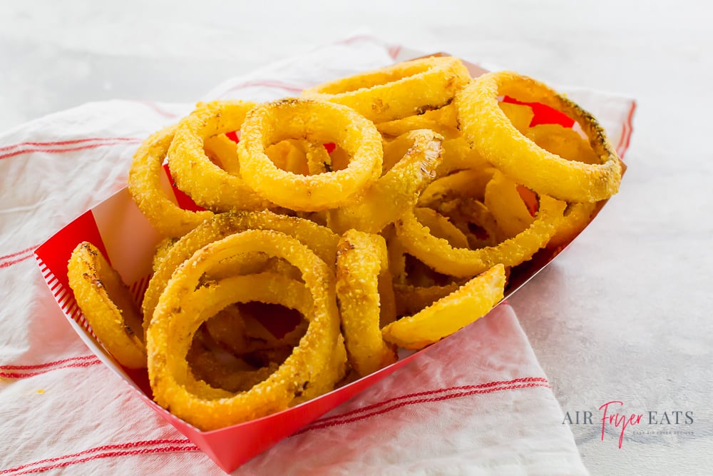 Onion rings in a fast food-style container on a kitchen towel