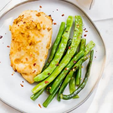 Overhead shot of ginger chicken with green beans on a white plate