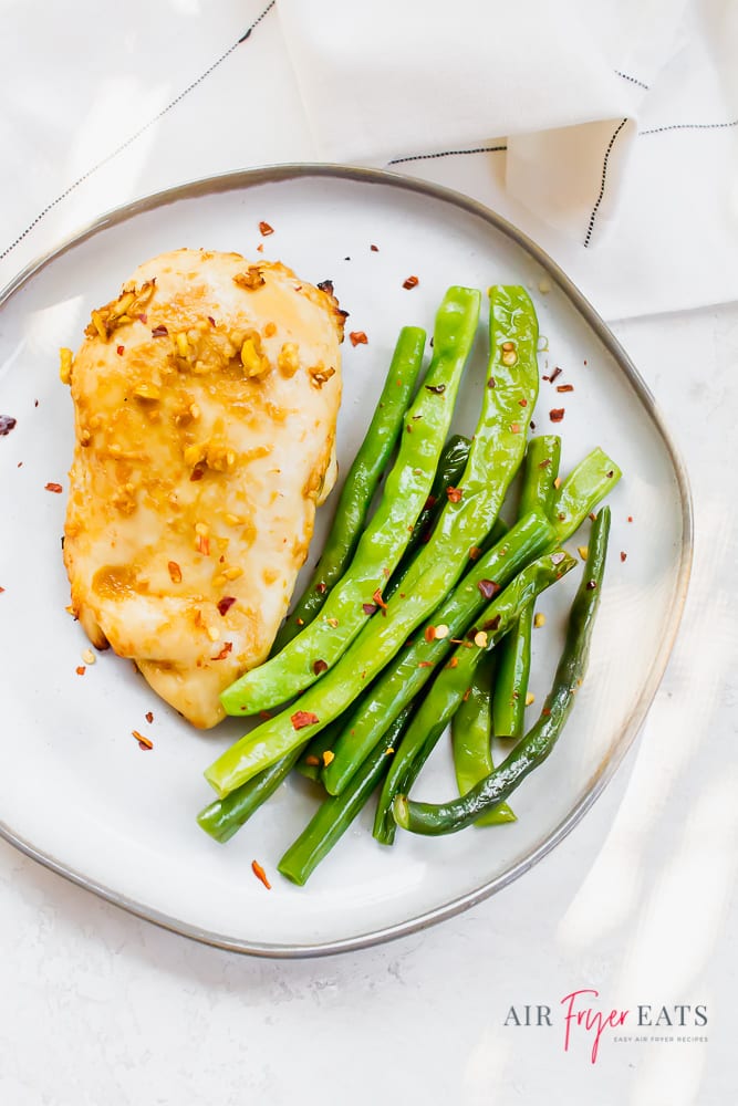 Overhead shot of ginger chicken with green beans on a white plate