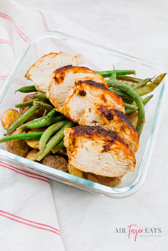 Seasoned chicken, green beans, and roasted potatoes in a meal prep container