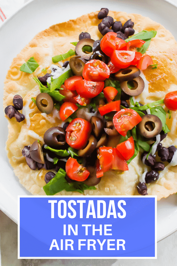 close-up overhead shot of a vegetarian tostada with black beans, tomatoes, and olives