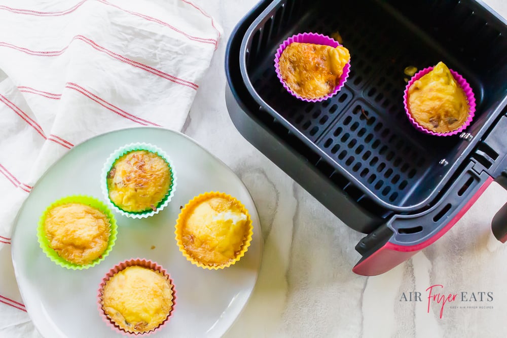 Scrambled egg cups in an air fryer basket and on a white plate
