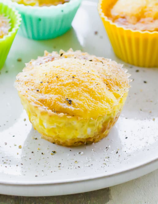 Close-up of a scrambled egg cup with tater tots sprinkled with salt and pepper