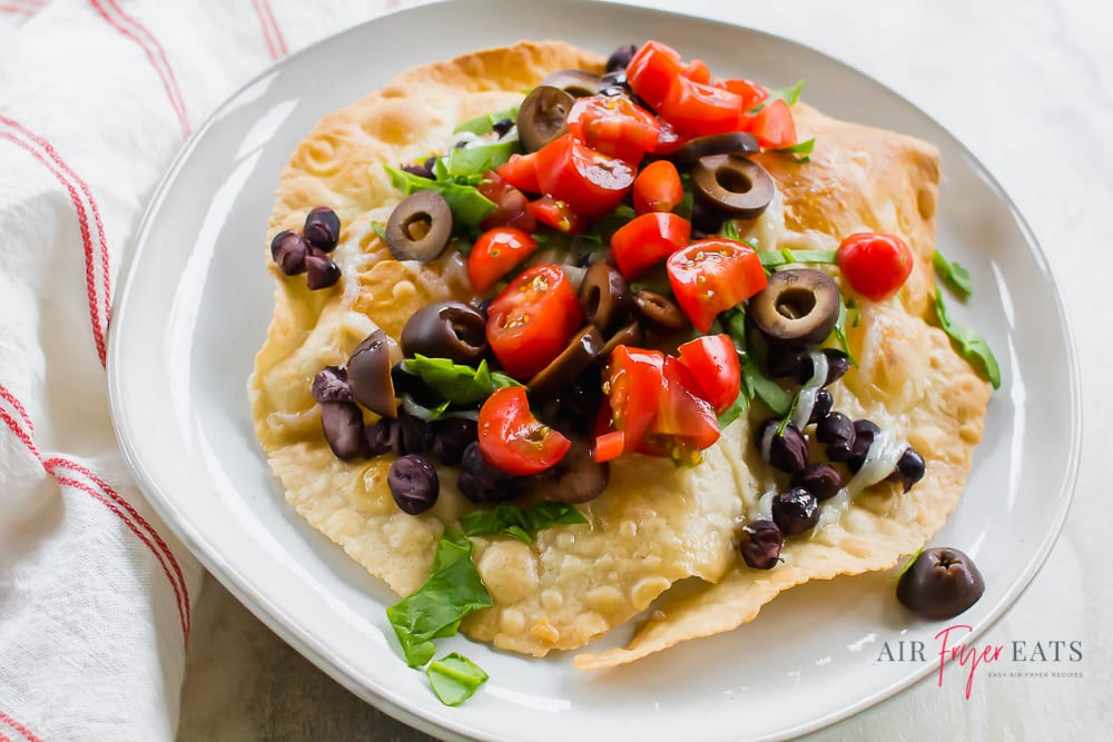 vegetarian tostada covered with black beans, tomatoes, olives, and lettuce