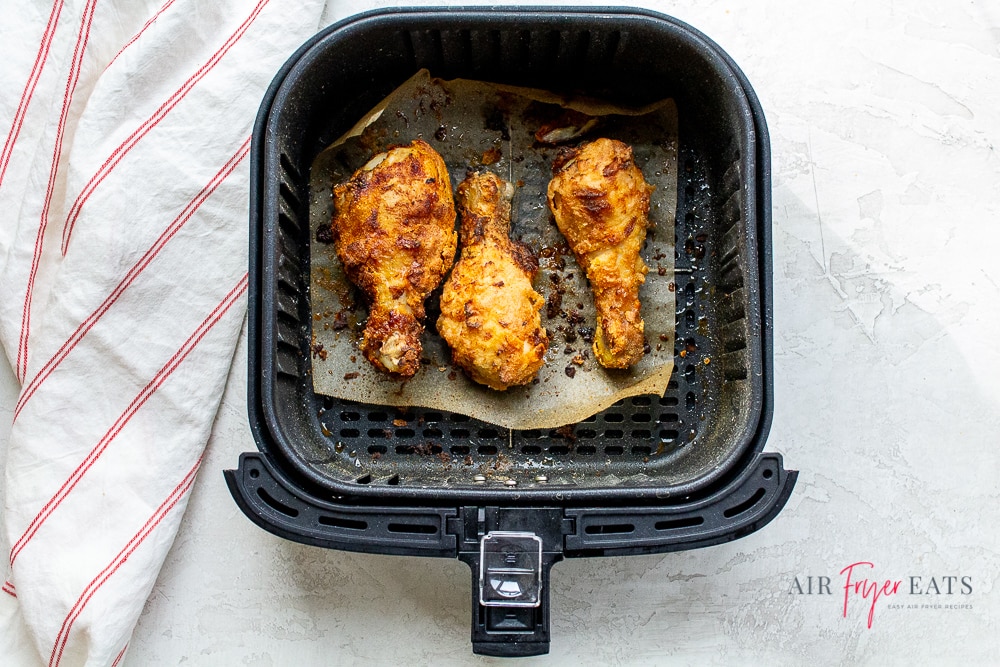 black air fryer basket with cooked crispy brown air fryer chicken inside