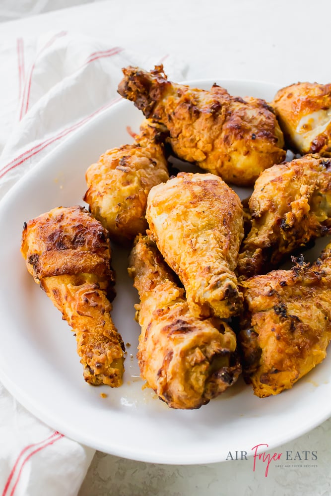 vertical photo of a white plate full of crispy brown air fried chicken legs