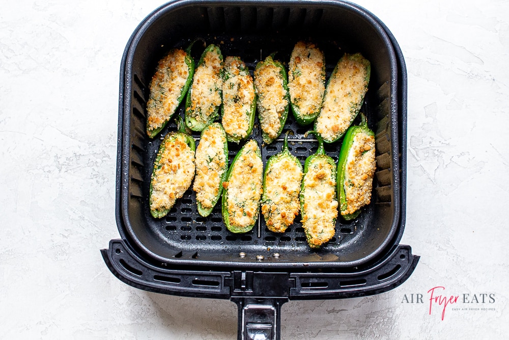 cooked air fryer jalapeno poppers in a black air fryer basket