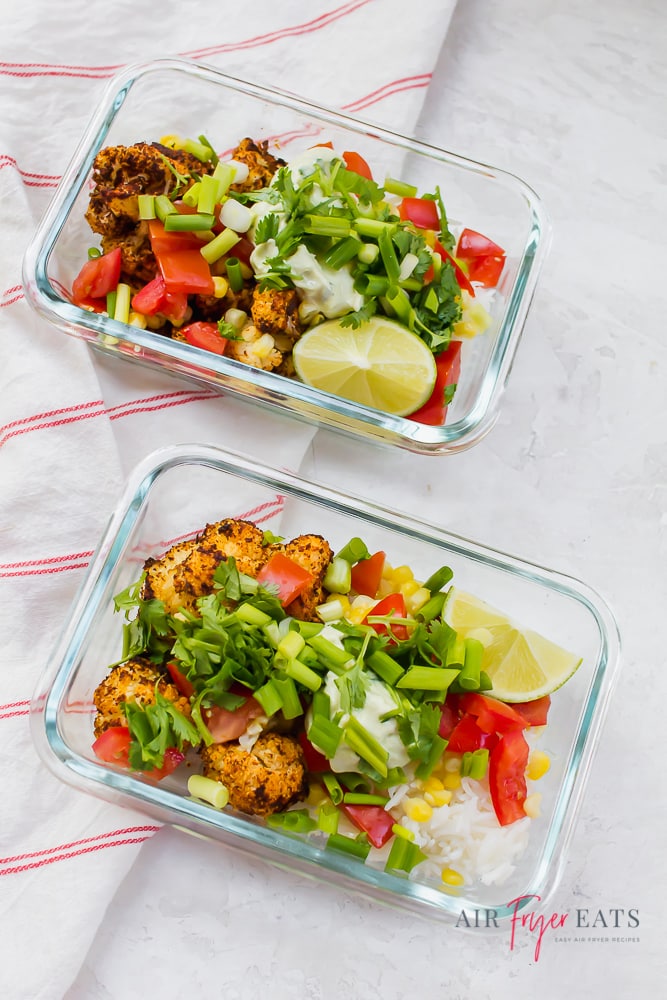 Two meal prep containers of air fryer cauliflower taco bowl ingredients